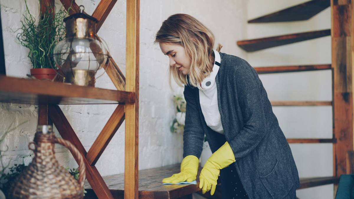 Woman spraying green home eco cleaning solution on kitchen counter with reusable cloth